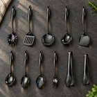 Okura 11-piece utensil set in black arranged on a charcoal kitchen countertop