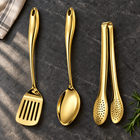 Okura 3-piece utensil set in gold arranged on a charcoal kitchen countertop