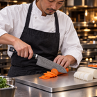 A Japanese chef using the Shiden Santoku Knife on a titanium cutting board in a professional kitchen