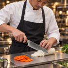 A Japanese chef using the Haku Santoku Knife on a titanium cutting board in a professional kitchen