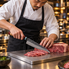 A Japanese chef using the Tenryu Gyuto Chef Knife on a titanium cutting board in a professional kitchen