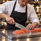 A Japanese chef using the Genkai Gyuto Chef Knife on a titanium cutting board in a professional kitchen