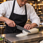 A Japanese chef using the Arashi Kiritsuke Knife on a titanium cutting board in a professional kitchen