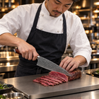 A Japanese chef using the Kurama Kiritsuke Knife on a titanium cutting board in a professional kitchen