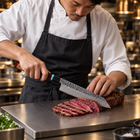 A Japanese chef using the Tenryu Kiritsuke Knife on a titanium cutting board in a professional kitchen