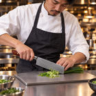 A Japanese chef using the Asama Nakiri Knife on a titanium cutting board in a professional kitchen