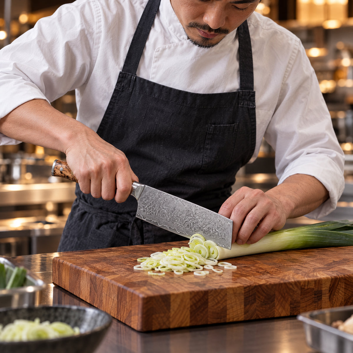 A Japanese chef using the Hayate Nakiri Knife on a wooden cutting board in a professional kitchen