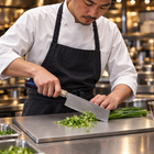 A Japanese chef using the Raiko Nakiri Knife on a titanium cutting board in a professional kitchen