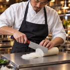 A Japanese chef using the Shinzan Nakiri Knife on a titanium cutting board in a professional kitchen