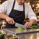 A Japanese chef using the Takamori Nakiri Knife on a titanium cutting board in a professional kitchen