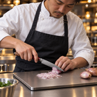 A Japanese chef using the Akagi Petty Knife on a titanium cutting board in a professional kitchen
