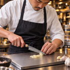 A Japanese chef using the Retsu Petty Knife on a titanium cutting board in a professional kitchen