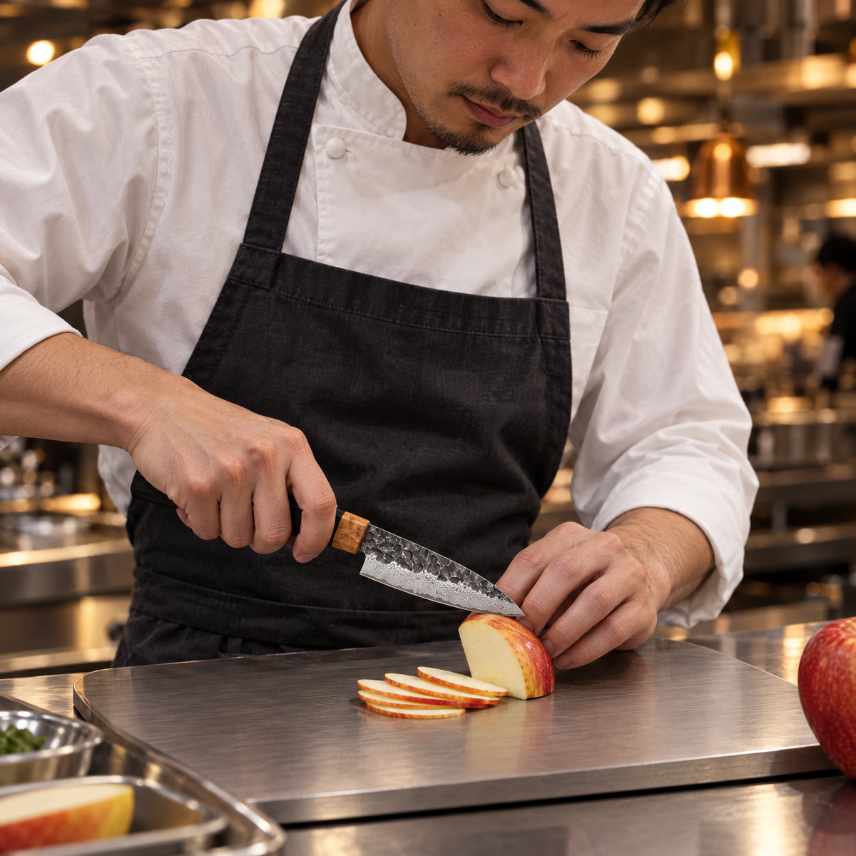 A Japanese chef using the Genbu Paring Knife on a titanium cutting board in a professional kitchen