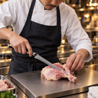 A Japanese chef using the Tsukikage Honesuki Boning Knife on a titanium cutting board in a professional kitchen