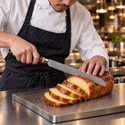 A Japanese chef using the Daigo Bread Knife on a titanium cutting board in a professional kitchen