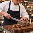 A Japanese chef using the Genkai Bread Knife on a wooden cutting board in a professional kitchen