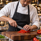A Japanese chef using the Kogane Utility Knife on a wooden cutting board in a professional kitchen