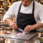 A Japanese chef using the Kongo Utility Knife on a titanium cutting board in a professional kitchen