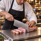 A Japanese chef using the Reimei Vegetable Cleaver Knife on a titanium cutting board in a professional kitchen