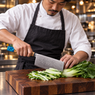 A Japanese chef using the Suijin Vegetable Cleaver Knife on a wooden cutting board in a professional kitchen