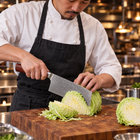 A Japanese chef using the Takamori Vegetable Cleaver Knife on a wooden cutting board in a professional kitchen