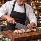 A Japanese chef using the Yamato Cleaver Knife on a wooden cutting board in a professional kitchen
