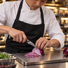 A Japanese chef using the Tsukikage Bird's Beak Peeling Knife on a titanium cutting board in a professional kitchen