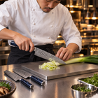 A Japanese chef using the Genkai 2-Piece Knife Set (Gyuto & Santoku) on a titanium cutting board in a professional kitchen