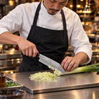 A Japanese chef using the Akatsuki Bunka Knife on a titanium cutting board in a professional kitchen