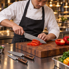 A Japanese chef using the Asahi 2-Piece Knife Set (Gyuto & Petty) on a wooden cutting board in a professional kitchen