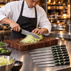 A Japanese chef using the Ibuki 9-Piece Knife Set on a wooden cutting board in a professional kitchen