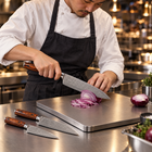 A Japanese chef using the Asahi 3-Piece Knife Set (Gyuto, Nakiri & Petty) on a titanium cutting board in a professional kitchen
