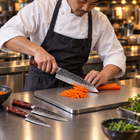A Japanese chef using the Hagane 2-Piece Knife Set (Gyuto & Utility) on a titanium cutting board in a professional kitchen