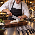 A Japanese chef using the Kurogane Damascus Knife Set on a wooden cutting board in a professional kitchen