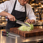 A Japanese chef using the Retsu 2-Piece Knife Set (Gyuto & Petty) on a wooden cutting board in a professional kitchen