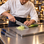 A Japanese chef using the Seiryu 2-Piece Knife Set (Gyuto & Utility) on a titanium cutting board in a professional kitchen