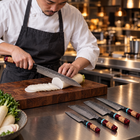 A Japanese chef using the Tenryu Damascus Knife Set on a wooden cutting board in a professional kitchen