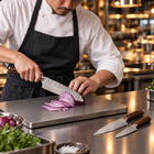 A Japanese chef using the Taiga 3-Piece Knife Set (Gyuto, Nakiri & Utility) on a titanium cutting board in a professional kitchen