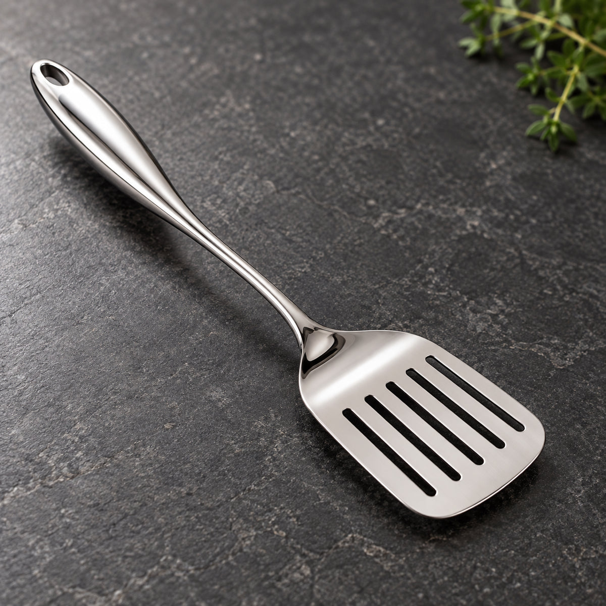 Rounded-handle slotted turner on a charcoal kitchen countertop