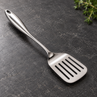 Rounded-handle slotted turner on a charcoal kitchen countertop