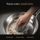 Hand scrubbing an Okura titanium pan in small circles with warm water