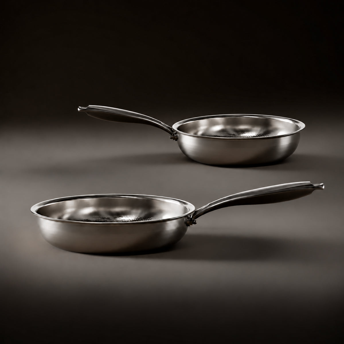Two same-size titanium pans in side view with natural depth perspective