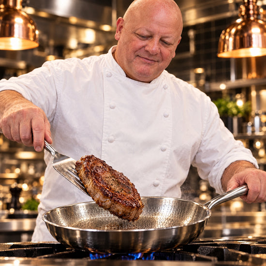 Chef Gregory lifting a seared steak from an Okura hammered titanium pan with a metal spatula