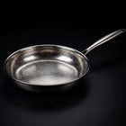 Hand-hammered titanium frying pan searing food, naturally non-stick PFAS-free cookware by Okura